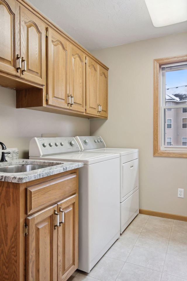 laundry room featuring cabinets, light tile patterned floors, and independent washer and dryer