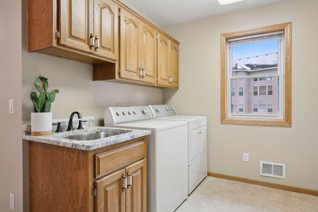 clothes washing area featuring cabinets, sink, and washer and clothes dryer