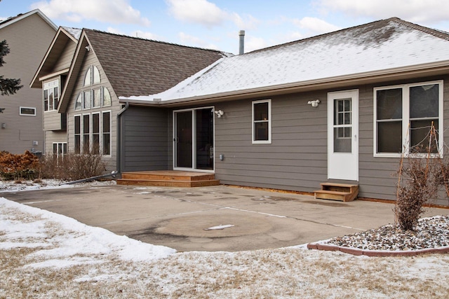 snow covered rear of property with a patio