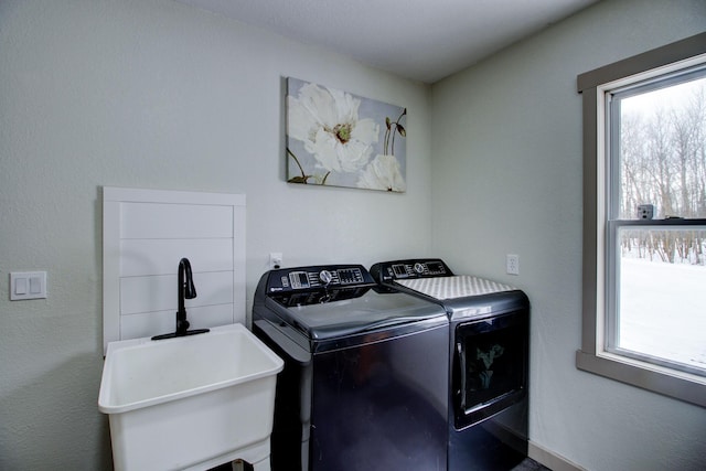 washroom featuring laundry area, washing machine and dryer, a sink, and a healthy amount of sunlight