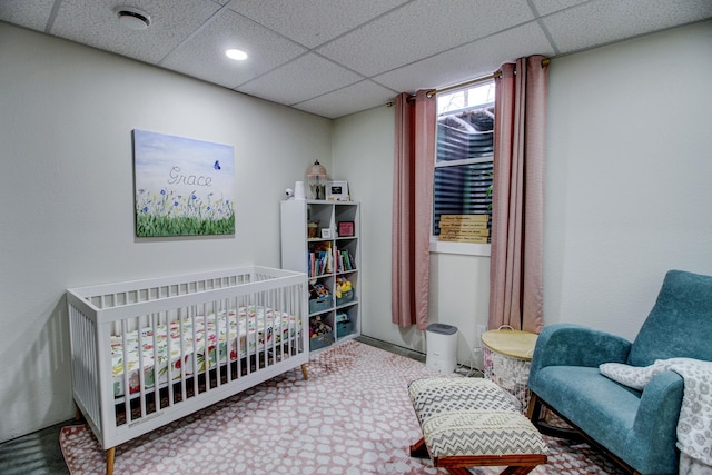 bedroom featuring a crib and a drop ceiling