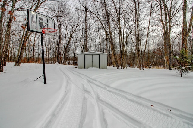 snowy yard with a storage shed