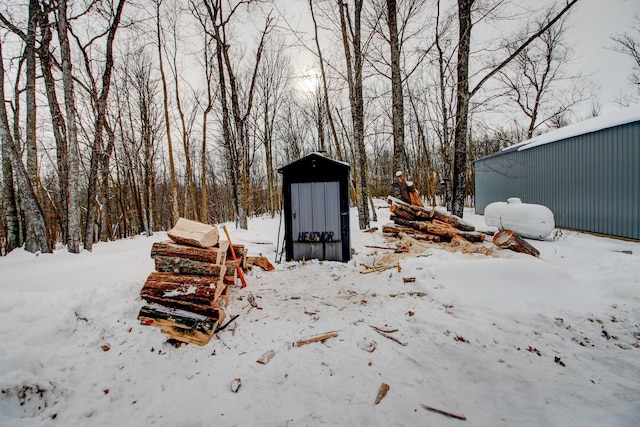 snow covered structure featuring a garage and an outdoor structure