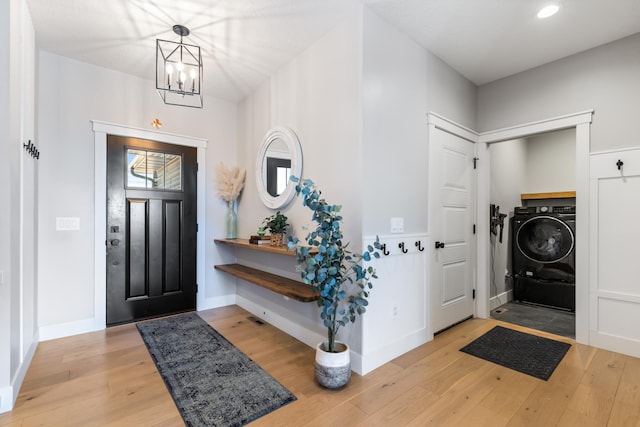 foyer entrance featuring light hardwood / wood-style floors, an inviting chandelier, and washer / clothes dryer