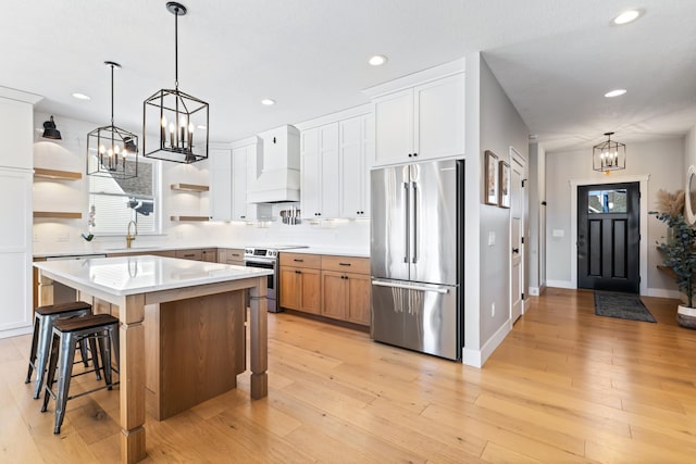 kitchen with sink, premium range hood, white cabinets, a center island, and stainless steel appliances