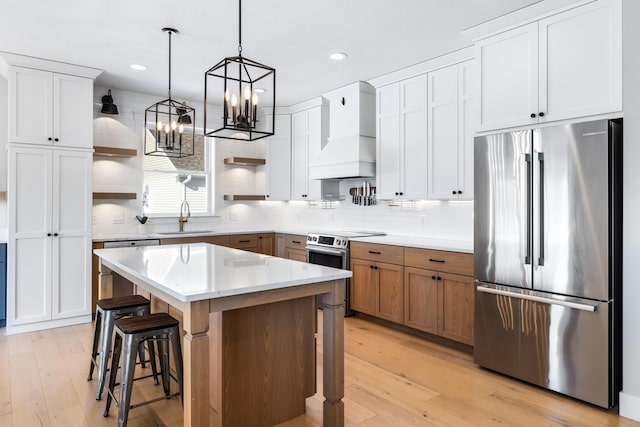 kitchen with a kitchen island, custom exhaust hood, white cabinetry, stainless steel appliances, and sink