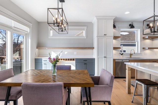 dining space featuring sink, light hardwood / wood-style floors, and a notable chandelier