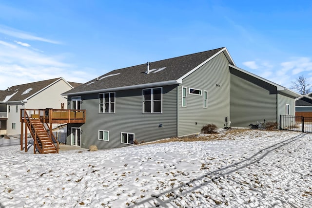 snow covered house with a wooden deck