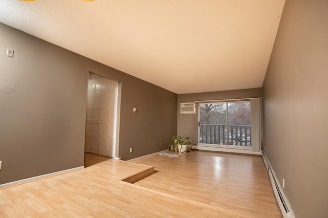 unfurnished room featuring a wall mounted AC, baseboard heating, and light hardwood / wood-style flooring