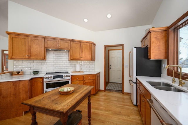 kitchen with sink, stainless steel fridge, high end white range, dishwasher, and backsplash