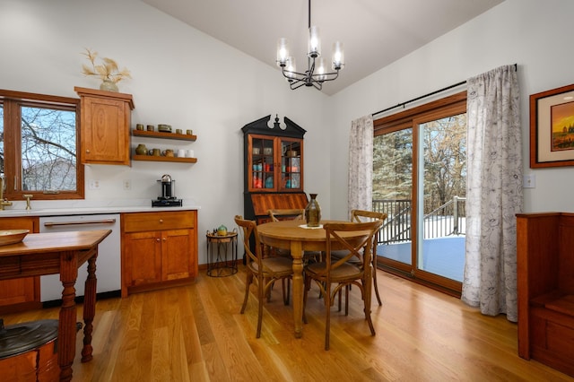 dining area with vaulted ceiling, a chandelier, and light wood-type flooring