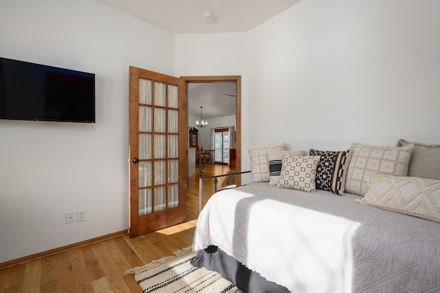 bedroom with an inviting chandelier, hardwood / wood-style floors, and french doors