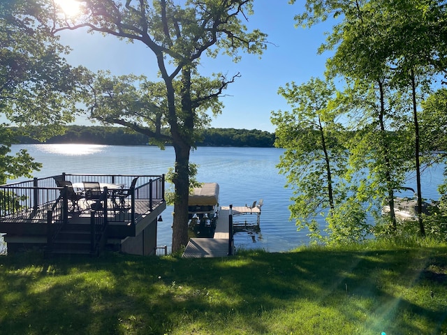 view of dock featuring a water view and a yard