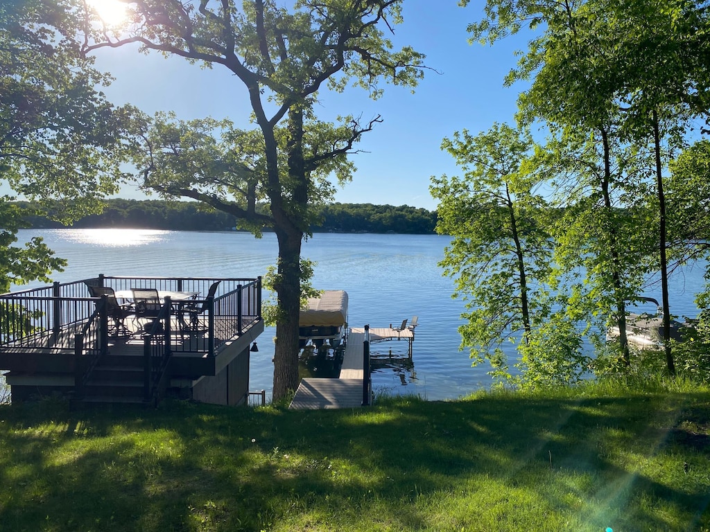 view of dock with a yard and a water view