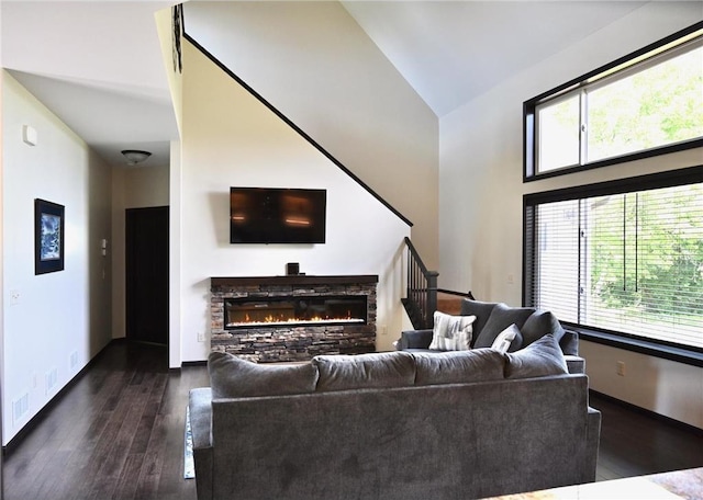 living room featuring high vaulted ceiling, dark hardwood / wood-style floors, and a stone fireplace