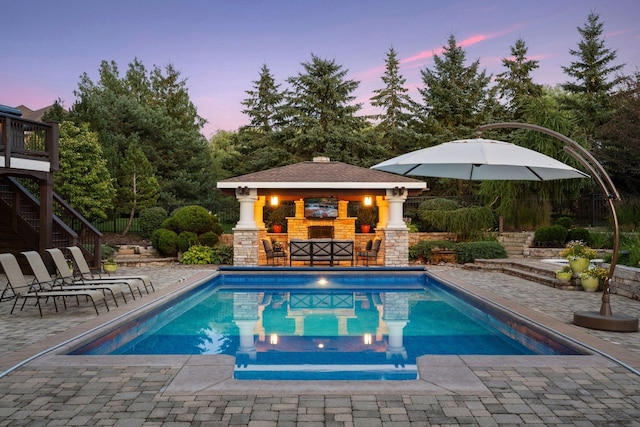 pool at dusk with a gazebo, exterior bar, and a patio area