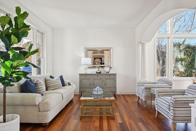 sitting room with a healthy amount of sunlight, dark wood-type flooring, and ornate columns