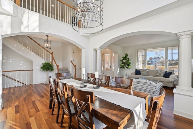 dining area with a chandelier, a towering ceiling, and hardwood / wood-style flooring