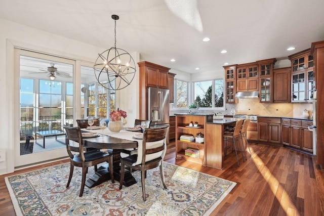 dining room with dark wood-type flooring and ceiling fan with notable chandelier