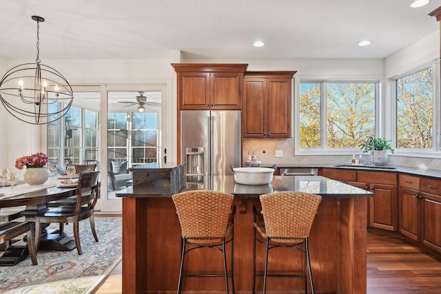 kitchen with dark stone counters, appliances with stainless steel finishes, a kitchen island, and sink