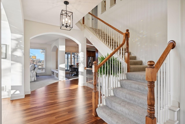 staircase featuring wood-type flooring and a chandelier