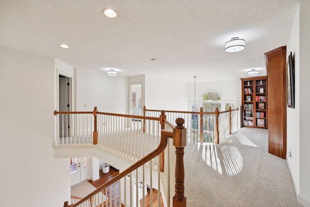 hall with light carpet and a textured ceiling