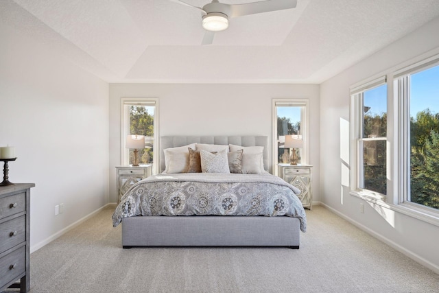 carpeted bedroom featuring ceiling fan and a raised ceiling