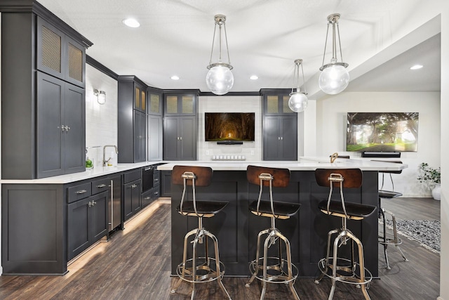 kitchen featuring hanging light fixtures, dark hardwood / wood-style flooring, a breakfast bar area, and a large island