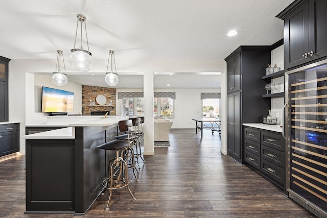 kitchen with wine cooler, dark hardwood / wood-style floors, a kitchen island, a breakfast bar, and hanging light fixtures