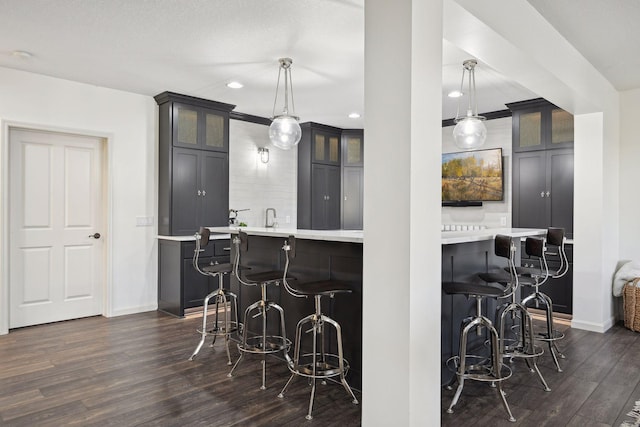 kitchen featuring dark wood-type flooring, a kitchen bar, and decorative light fixtures