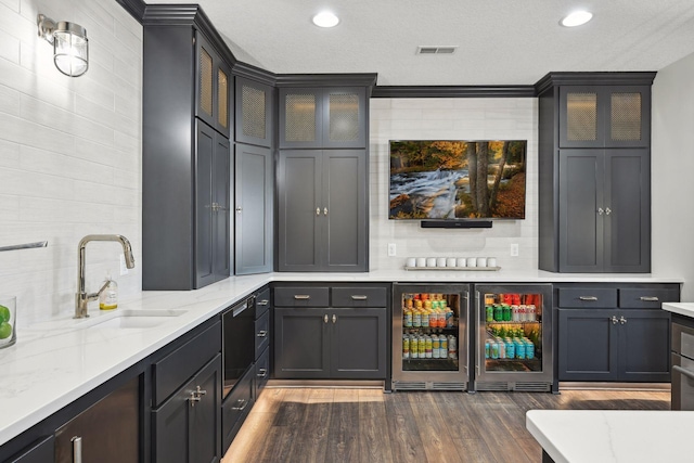 bar with dark hardwood / wood-style floors, sink, light stone counters, and beverage cooler