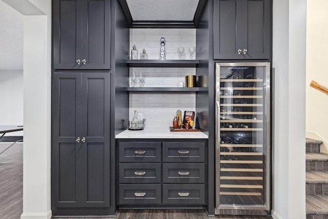 bar featuring a textured ceiling, ornamental molding, wine cooler, and dark hardwood / wood-style floors