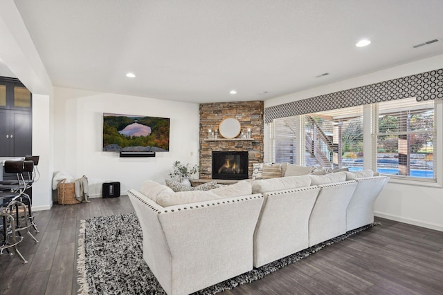 living room with dark hardwood / wood-style flooring and a stone fireplace