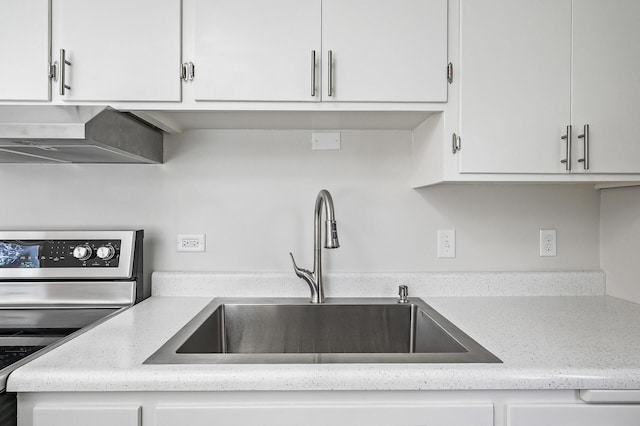 kitchen featuring stainless steel electric stove, white cabinetry, and sink