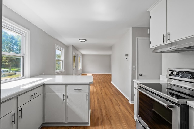 kitchen featuring kitchen peninsula, electric range, white cabinets, and light hardwood / wood-style floors