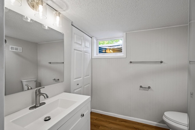 bathroom with wood-type flooring, vanity, a textured ceiling, and toilet