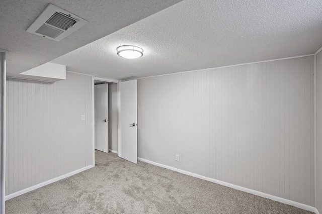 basement with light carpet, wood walls, and a textured ceiling