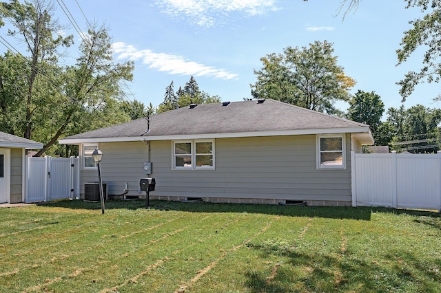 rear view of property with a yard and central AC