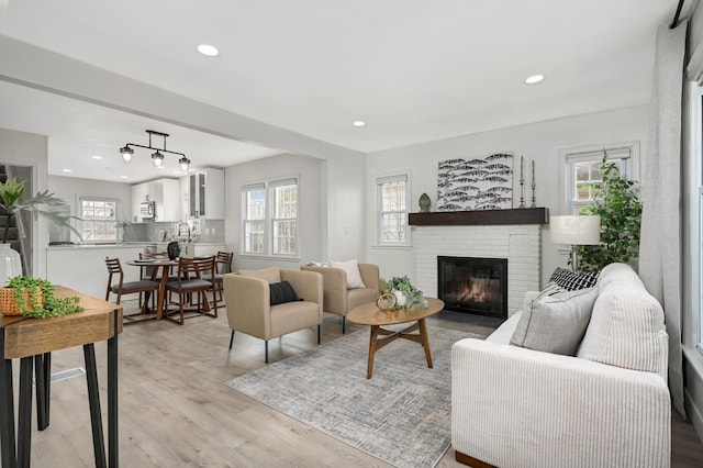 living room featuring light hardwood / wood-style flooring, a healthy amount of sunlight, and a fireplace