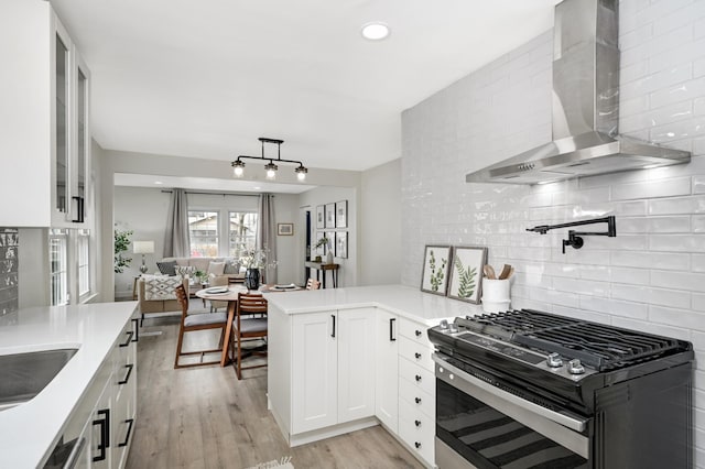 kitchen featuring white cabinetry, appliances with stainless steel finishes, kitchen peninsula, and wall chimney range hood