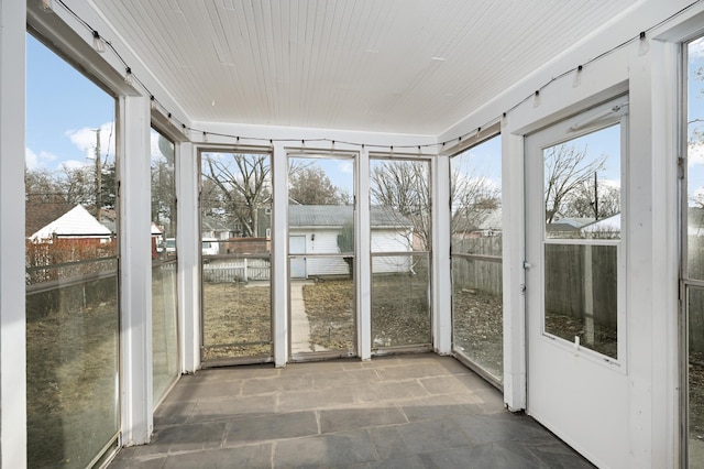 unfurnished sunroom featuring a healthy amount of sunlight and wooden ceiling