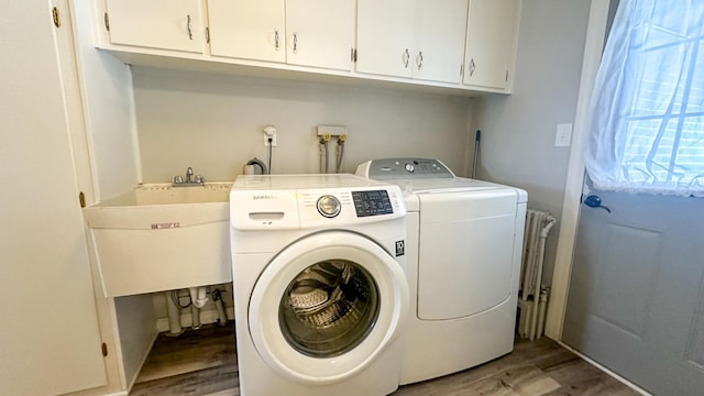 clothes washing area with cabinet space, light wood-style flooring, independent washer and dryer, and a sink