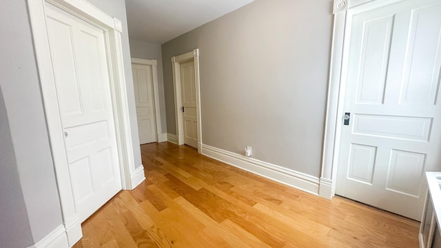 corridor featuring light wood-type flooring and baseboards