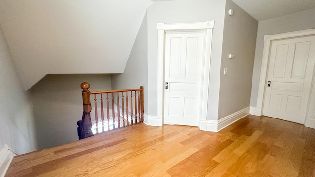 additional living space featuring baseboards, lofted ceiling, and wood finished floors