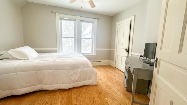 bedroom with a baseboard radiator, baseboards, ceiling fan, and light wood finished floors