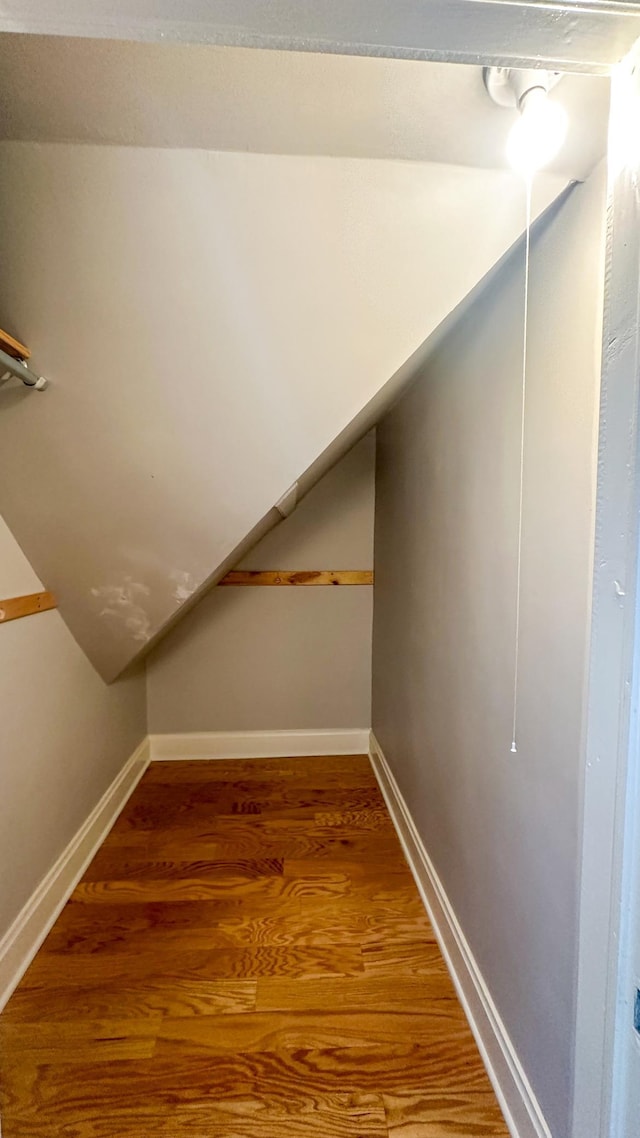 interior space featuring baseboards, wood finished floors, and vaulted ceiling