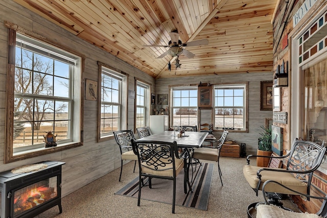 carpeted dining area featuring lofted ceiling, wooden ceiling, ceiling fan, and wood walls