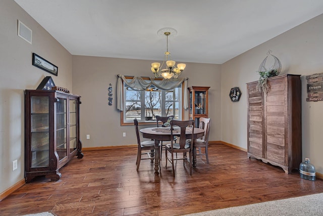 dining room with dark hardwood / wood-style flooring and a chandelier