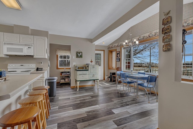 interior space with vaulted ceiling, dark hardwood / wood-style flooring, pendant lighting, white appliances, and white cabinets