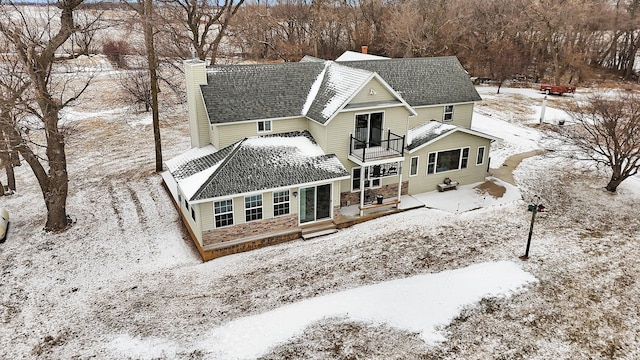 snow covered house featuring a balcony